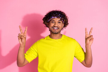 Photo of glad funky positive man wear trendy yellow clothes demonstrate v-sign symbol isolated on...
