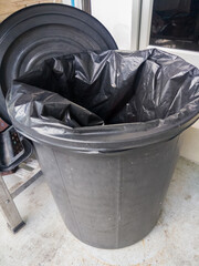A black garbage bag in a black plastic trash can.