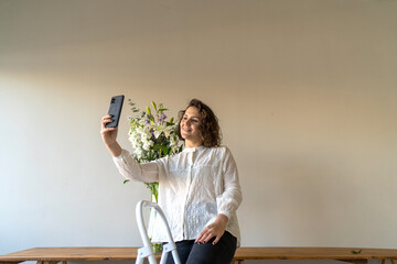 Woman florist taking selfie with flowers