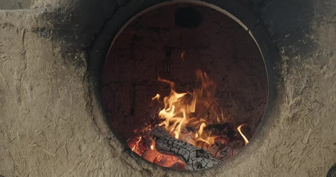 Burning fire in a traditional clay oven tandoor. Uzbek bakery. Firewood burning in a clay Uzbek oven to bake samosa or bread