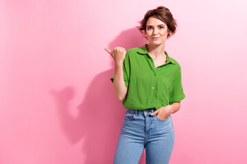 Photo of adorable pretty young woman dressed green shirt pointing thumb empty space isolated pink...