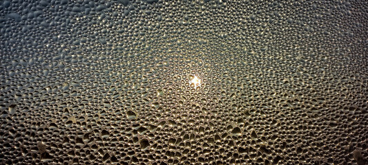 Real Photo of Water Drops on Window Glass. The sun shines through a window covered with water drops	