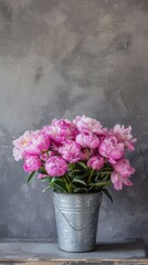 a bouquet of pink peonies arranged in an iron bucket, positioned on a table against a serene gray background, leaving ample space for text or additional elements.