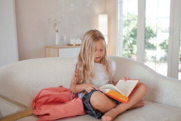 a little girl 6-7 years old is getting ready for school, the girl is dressed in a light-colored top...