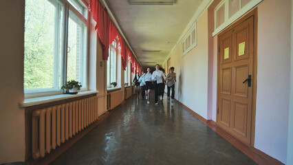 A down-syndrome school boy with group of children in corridor, running.