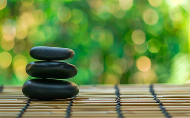 Stacked Black Spa Stones on Bamboo Mat With Green Bokeh Background