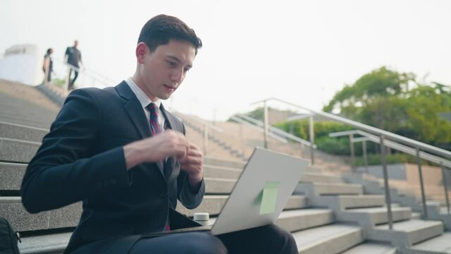 Young handsome business man sit down on the stairs using laptop computer filling up online job application, urban job opportunity, job search, unemployed person, wireless technology with business 