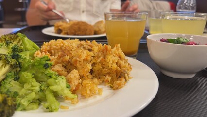 Broccoli with a dish of pilaf on the table while dining with friends.