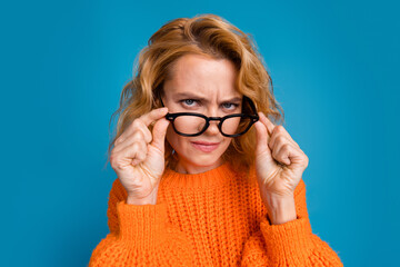Photo of funny woman wear stylish orange clothes look suspiciously spectacles isolated on blue...