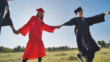 College graduates holding hands run in a round dance.