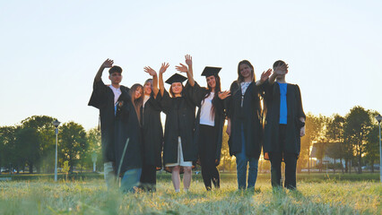 Student alumni waving at sunset.