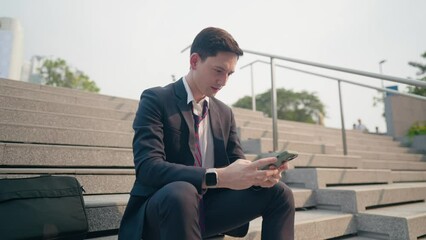 Young businessman sitting on the staircase looking at smartphone waiting for good news from company, urban job opportunity, white guy sits on staircase alone scrolling down cellphone, work pressure  - Powered by Adobe