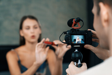 Man filming video on young woman making beauty and cosmetic tutorial video content for social...