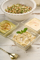Middle Eastern cuisine: baba ghanoush closeup in a plate on the table. Horizontal view from above and behind a Tabbouleh salad. Tabouli salad with fresh parsley