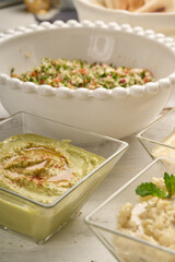 Middle Eastern cuisine: baba ghanoush closeup in a plate on the table. Horizontal view from above and behind a Tabbouleh salad. Tabouli salad with fresh parsley