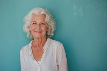 A woman with white hair is smiling in front of a blue wall