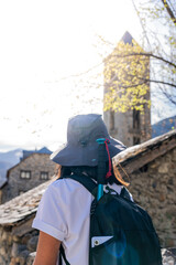 Woman with her back hiking at the entrance to a beautiful town with protected architecture on a beautiful spring morning