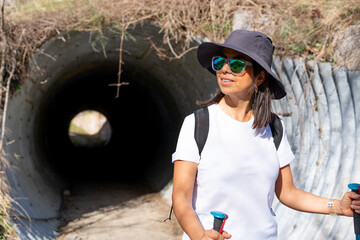 Young woman with sunglasses and backpack enjoying a beautiful spring morning just passing a tunnel...