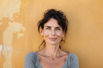 A woman smiles in front of a yellow wall