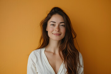 A woman with long hair is smiling in front of an orange wall