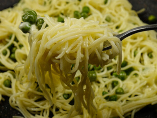  Italian spaghetti with green peas and grated cheese  on a fork

