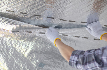 A worker is putting a sealant on the vapor barrier joints.