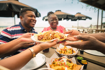 A group of African American friends shared tacos at a beach restaurant. Garifuna group from Guatemala. - obrazy, fototapety, plakaty