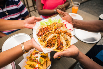 A group of African-American friends shared a plate of tacos at a restaurant.