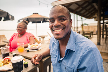Portrait of an African-American man hanging out with his family or friends at a beach restaurant.