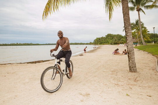 Young african american man riding a bicycle on the beach enjoying his vacation outdoors.