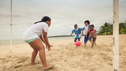 Girl waiting for the ball to reach the goal area to catch it, in a soccer game on the beach.