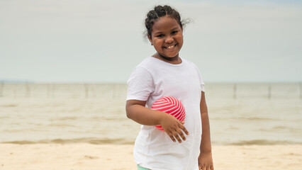 Portrait of a beautiful girl on the beach, holding a ball.