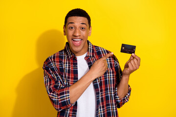 Photo of nice young man direct finger credit card wear shirt isolated on yellow color background