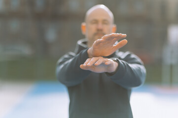 a bald man does an exercise with his hands. the boy does sports.