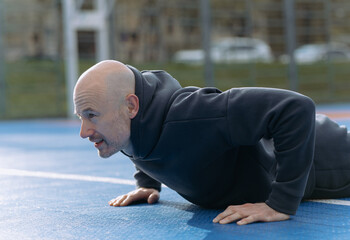 A young guy is exercising outdoors. A guy is doing a plank or push-up exercise