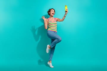 Full body portrait of impressed cheerful lady use smart phone make selfie arm waving hi isolated on...