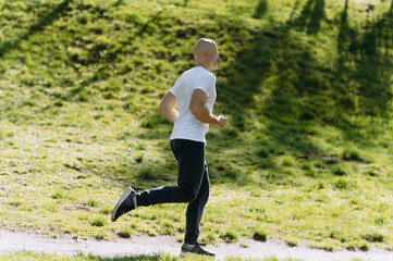 bald man runs in the park. morning run