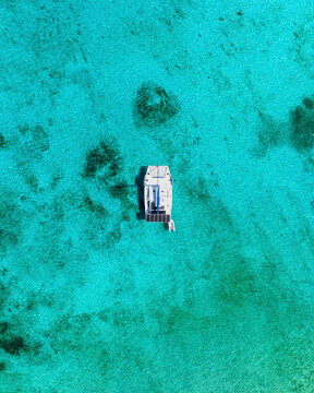 Aerial view of transparent turquoise waters and sailboat at Junkanoo Beach, Nassau, The Bahamas.