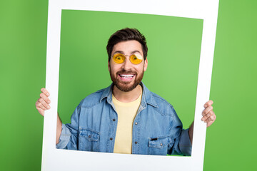 Photo of cheerful impressed guy wear denim jacket tacking photo isolated green color background