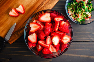 Large Glass Bowl Full of Stemmed and Halved Strawberries: Big bowl of fresh, ripe strawberries with their stems and leaves removed and sliced in half