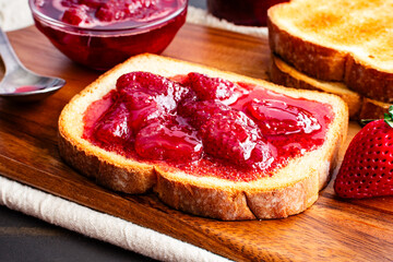 Slice of Toast Covered in Homemade Strawberry Preserves: Sliced and toasted white bread and homemade strawberry preserves with large pieces of fruit