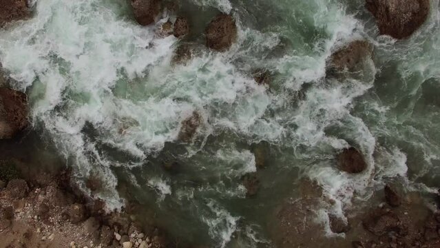River water flows rapidly through large rocks viewed from above 4K