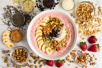 Strawberry Smoothie Bowl Loaded with Healthy Toppings: Fruit smoothy bowl with sliced banana, seeds, nuts, peanut butter, and dark chocolate chips