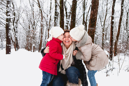 Daughters kissing mother in winter forest