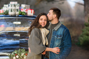 Obraz premium Couple kissing in vintage car with presents on roof