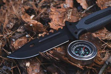Compass and knife on the ground in the forest. Concept of hunting and hiking.