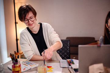 An artist engrossed in painting, her tools spread out on the table, capturing a moment of creative flow in a peaceful setting