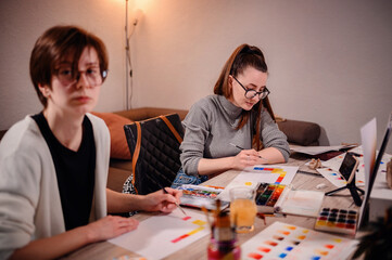 Two artists intently craft a color narrative, one with brush in hand, the other with pen poised,...