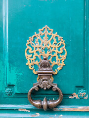 Vintage door handle and Detail of old wooden door. Background painted in tones of green or teal color with empty space for text. Close up. Selective focus.