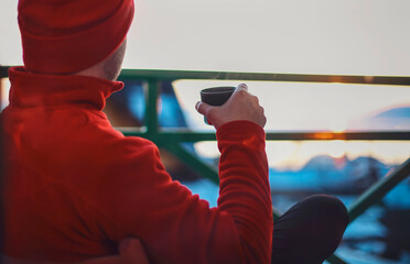 Man in winter clothing drinking hot herbal tea. Winter evening from a beautiful balcony in the...